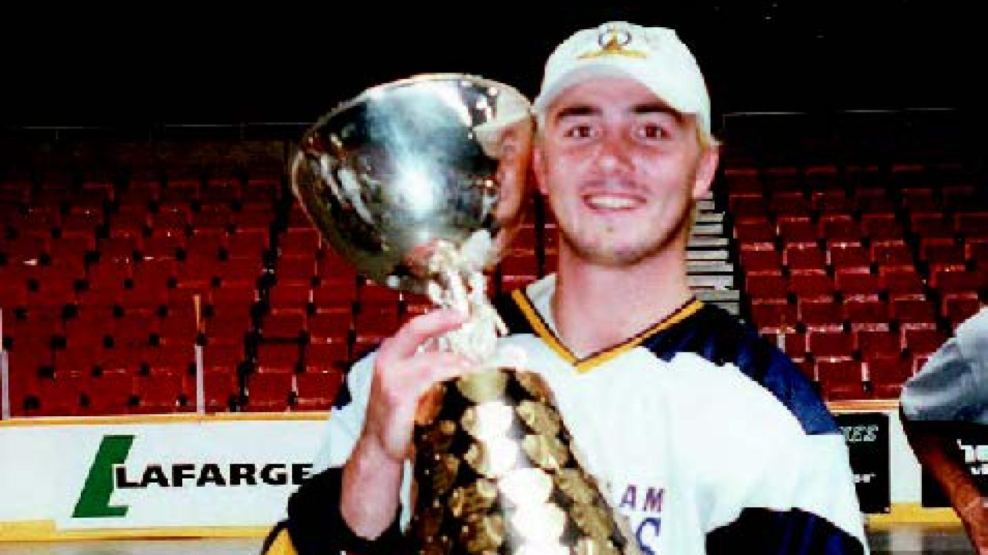 Travis Gillespie holds a large trophy inside an indoor arena.